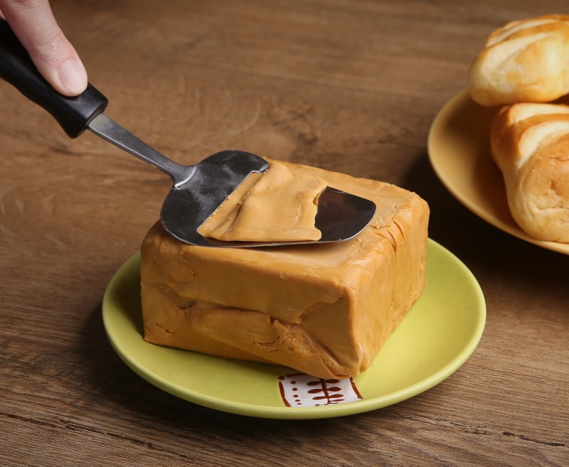 Un bloc de fromage brun norvégien et une trancheuse de fromage traditionnelle.