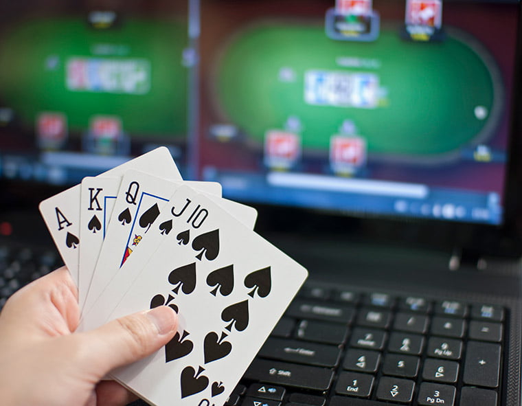 Poker main avec jeu en ligne en arrière-plan.