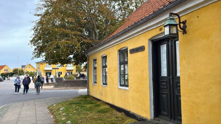 Des touristes passent devant une maison jaune à Skagen, au Danemark. Photo : David Nikel.